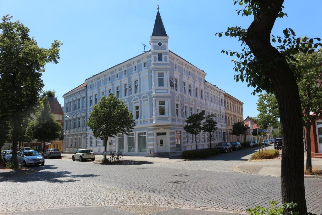 a large white building with a steeple on a street at Hotel Haus Singer in Wittenberge