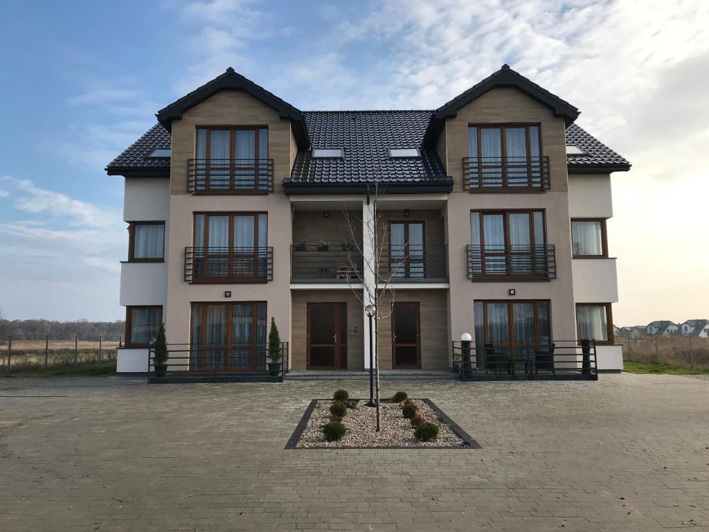 a large house with a tree in front of it at Apartament koloru morza - Lazur in Łeba