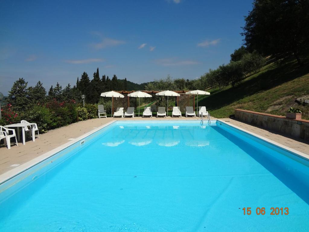 a large blue swimming pool with chairs and umbrellas at Fattoria Il Lago in Dicomano