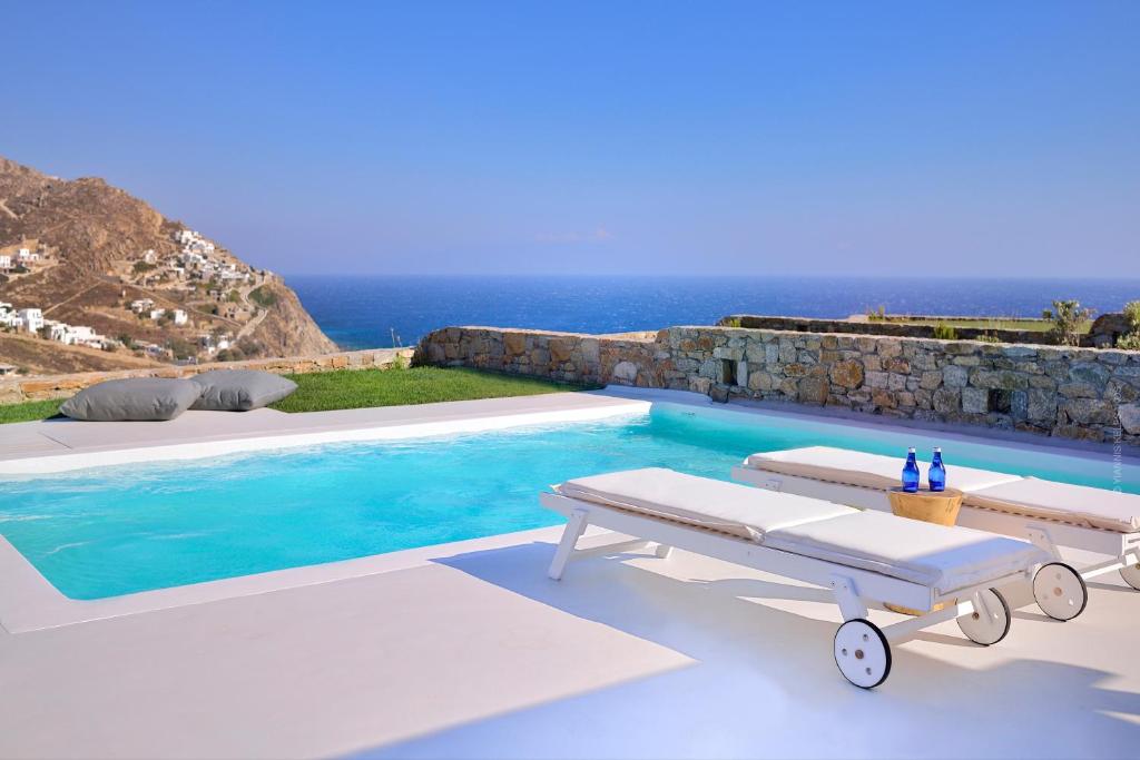 basen z dwoma ławkami i ocean w obiekcie Villa Kimothoe by Thalassa Residence Mykonos w mieście Elia