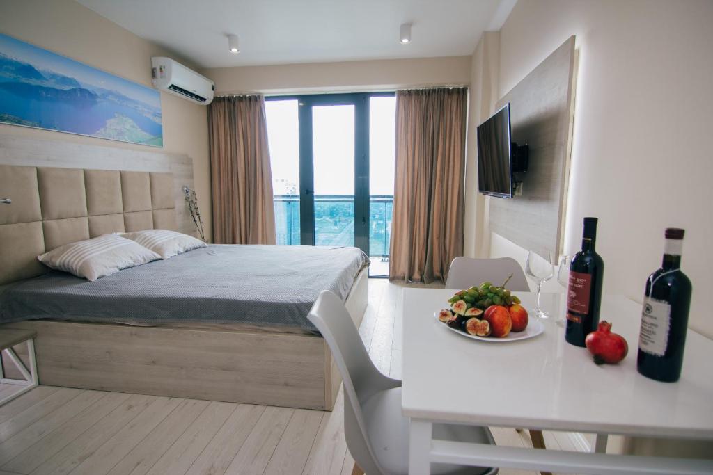 a bedroom with a bed and a table with a plate of fruit at Swiss Quality Apartments (Beach Tower) in Batumi