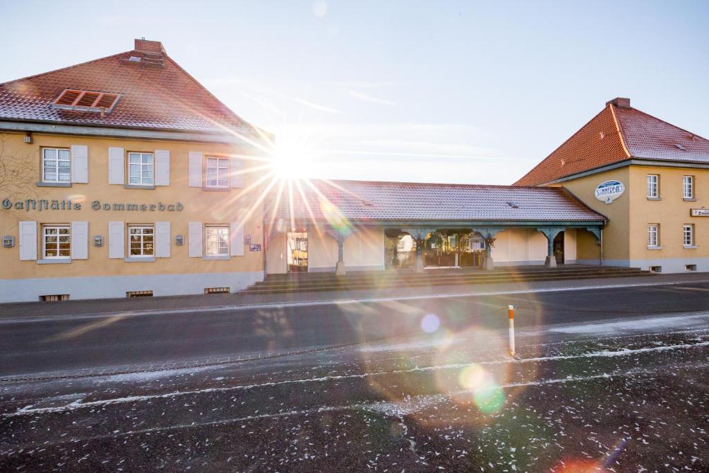 a building with the sun shining on a street at Hotel Am Sommerbad in Halberstadt