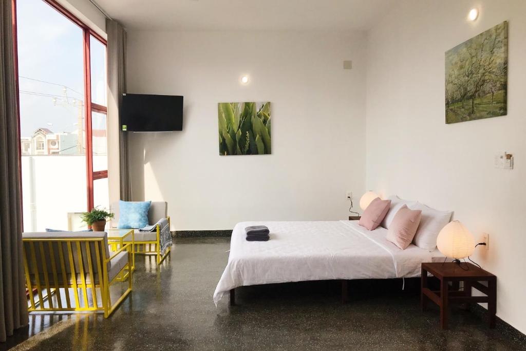 1 dormitorio con 1 cama con sábanas blancas y almohadas rosas en LaRose Cafe I Bed & Breakfast, en Quy Nhon
