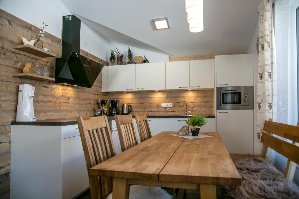 a kitchen with a wooden table and a kitchen with white cabinets at Appartement Alpenliebe in Rauris
