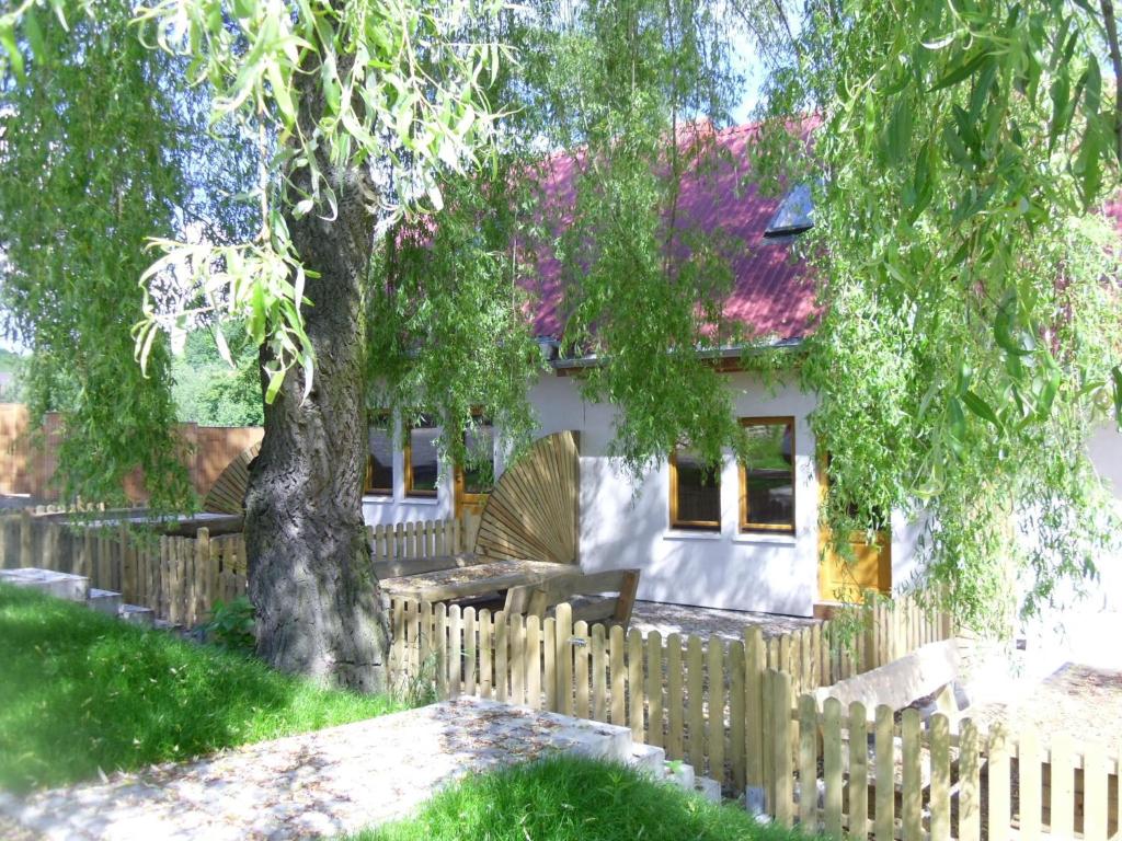 ein Holzzaun vor einem Haus mit einem Baum in der Unterkunft Domki Nad Jeziorem Karłowice in Karłowice