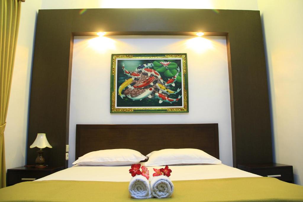 a bedroom with a bed with a picture on the wall at Nakula Guest House in Kuta