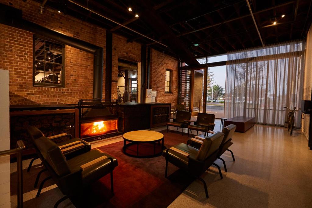 a living room with a fireplace and chairs and a table at The Premier Mill Hotel in Katanning