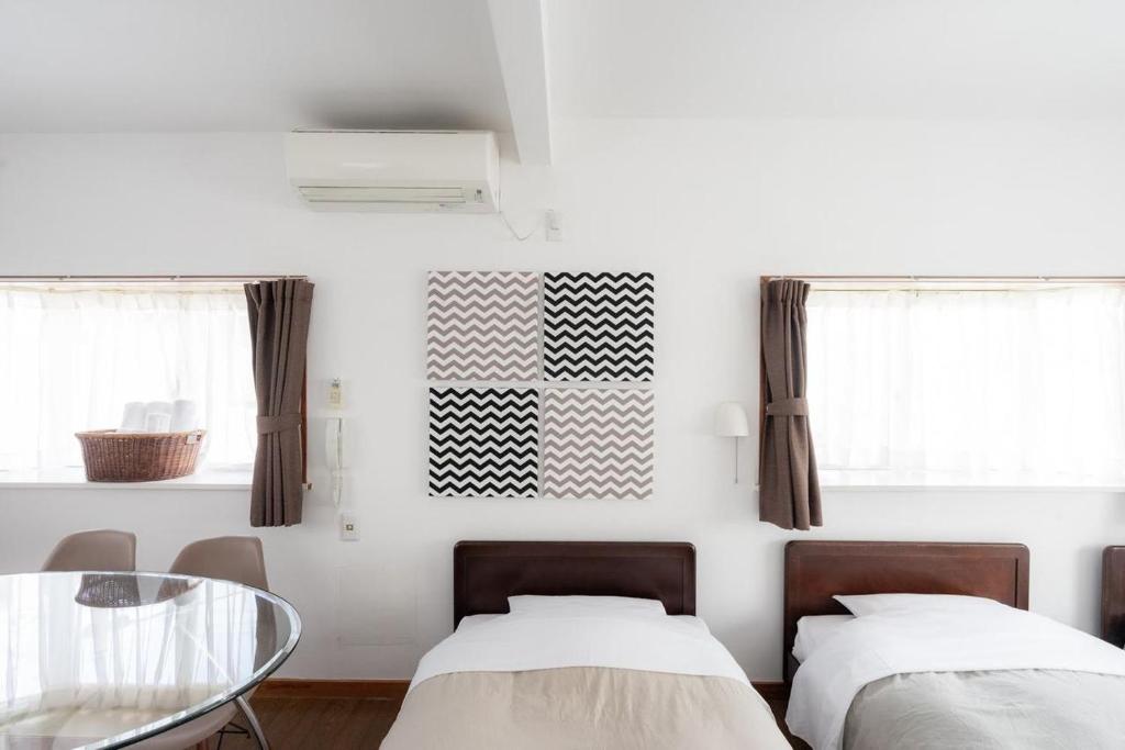 a bedroom with two beds and a glass table at Beach Side Inn Shirahama in Shimoda