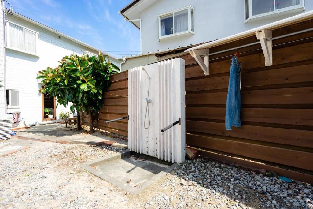 a fence with a white door next to a house at Beach Side Inn Shirahama in Shimoda