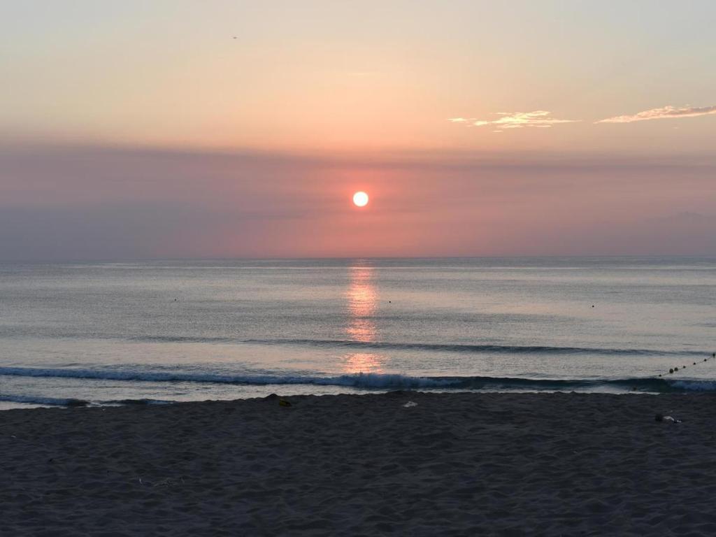 a sunset on the beach with the sun setting over the ocean at Beach Side Inn Shirahama in Shimoda