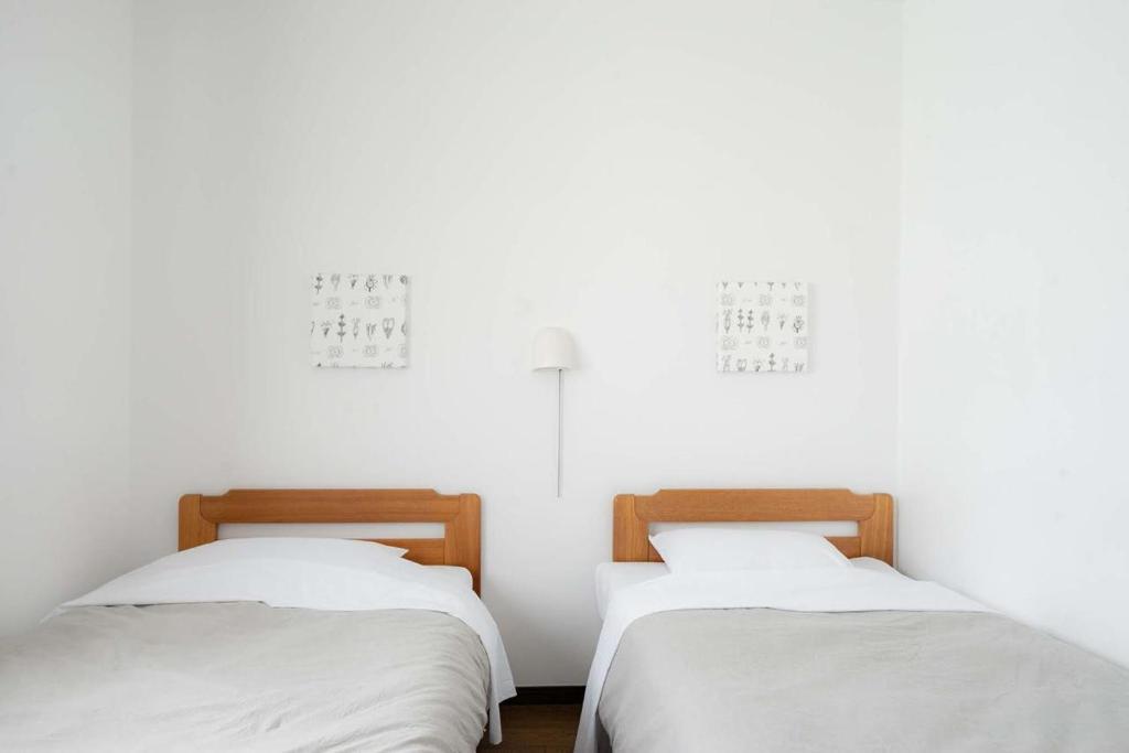two beds in a room with white walls at Beach Side Inn Shirahama in Shimoda