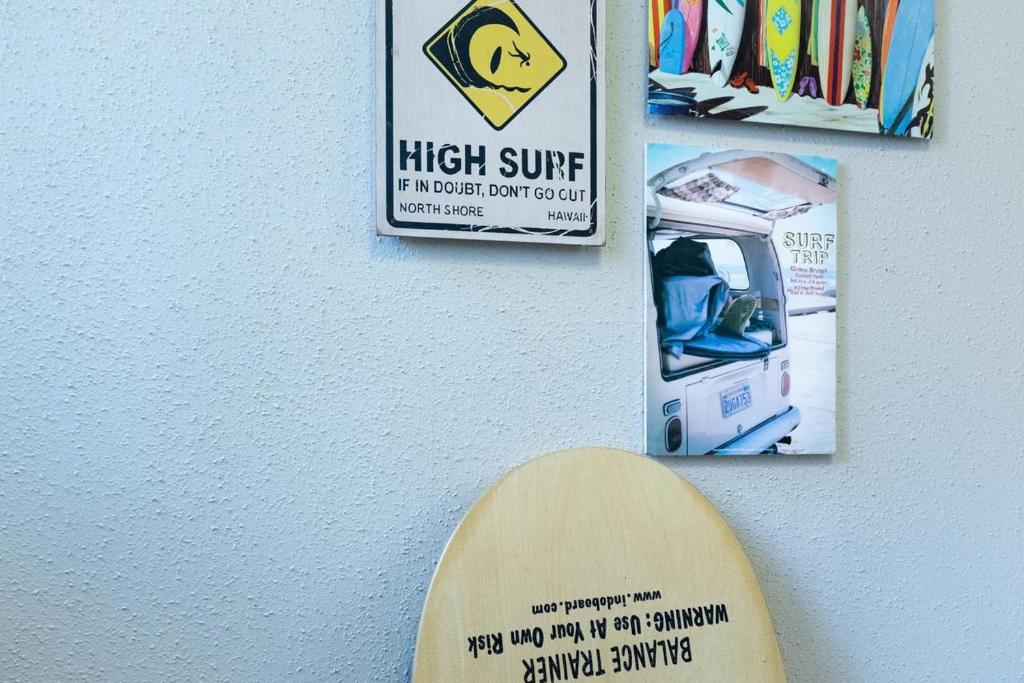 a surfboard on a wall with a high surf sign at Beach Side Inn Shirahama in Shimoda