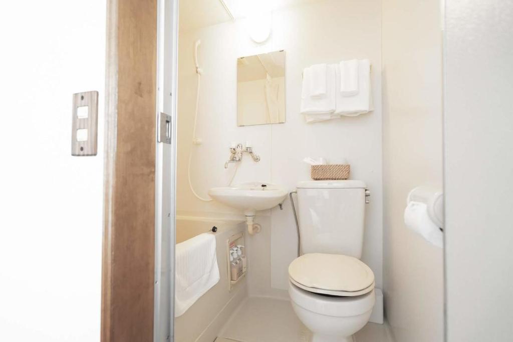 a white bathroom with a toilet and a sink at Beach Side Inn Shirahama in Shimoda