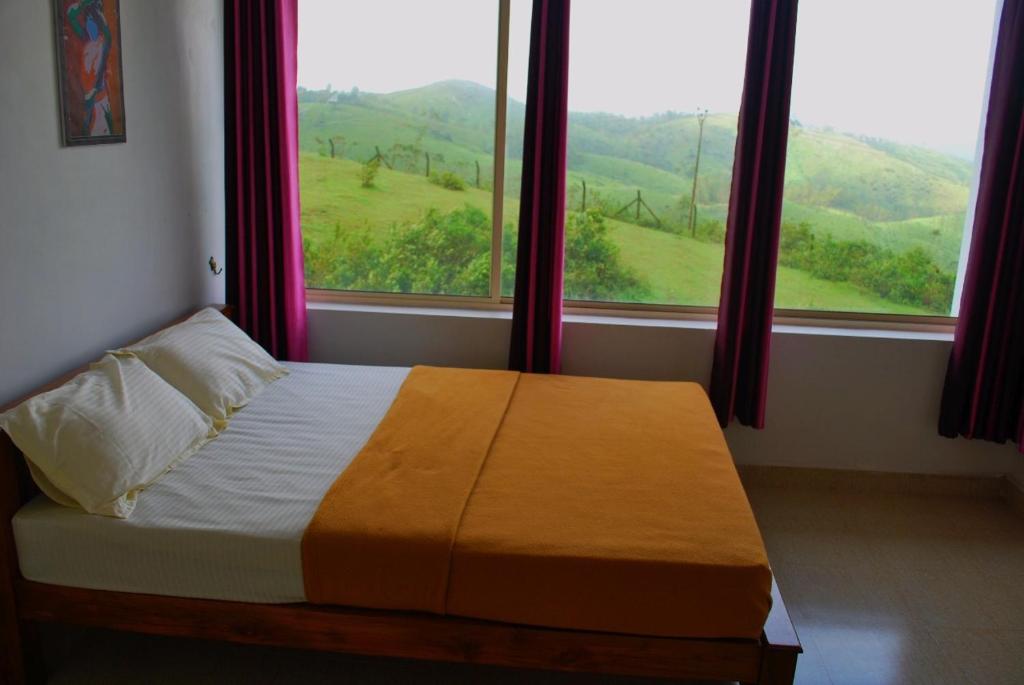 a bedroom with a bed and a window with a view at Vagamon Clouds in Vagamon