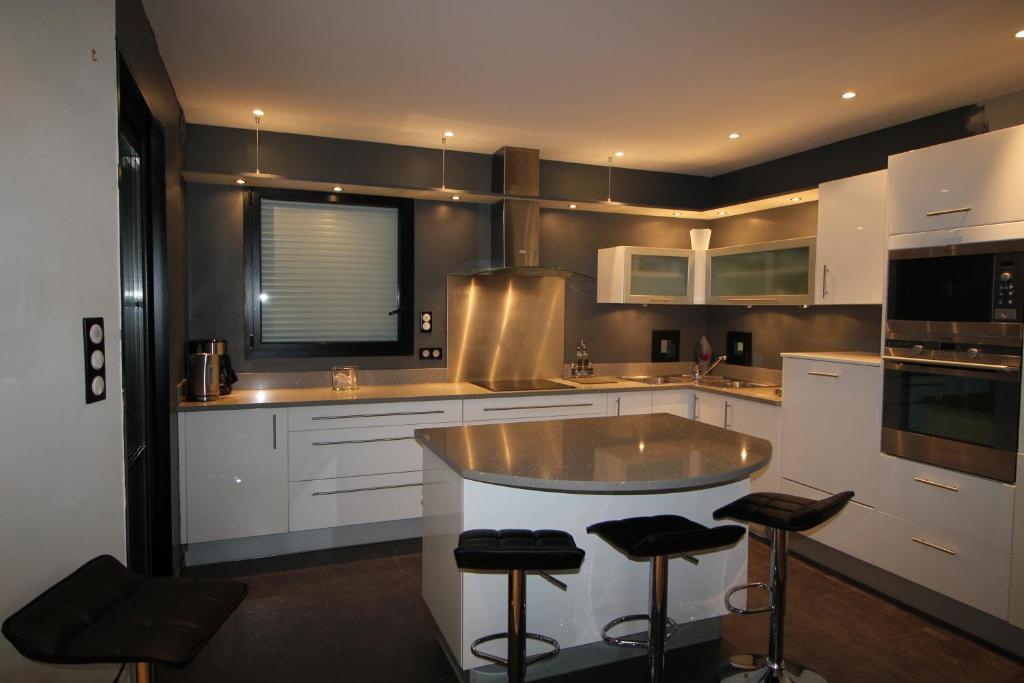 a kitchen with white cabinets and bar stools at Contemporary Villa of Kerseal in Gouesnach