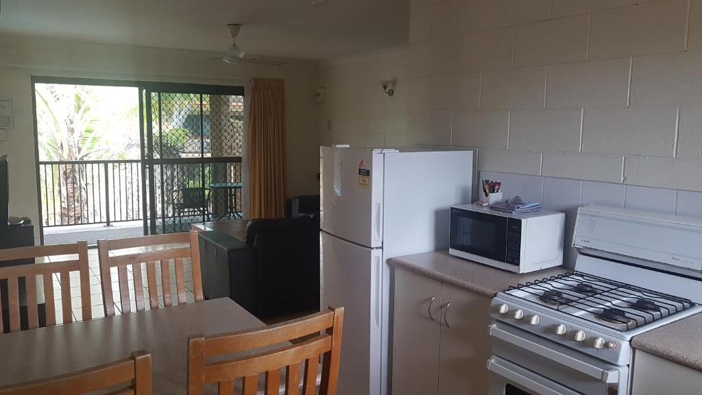 a kitchen with a white refrigerator and a microwave at Oasis Inn Apartments in Cairns