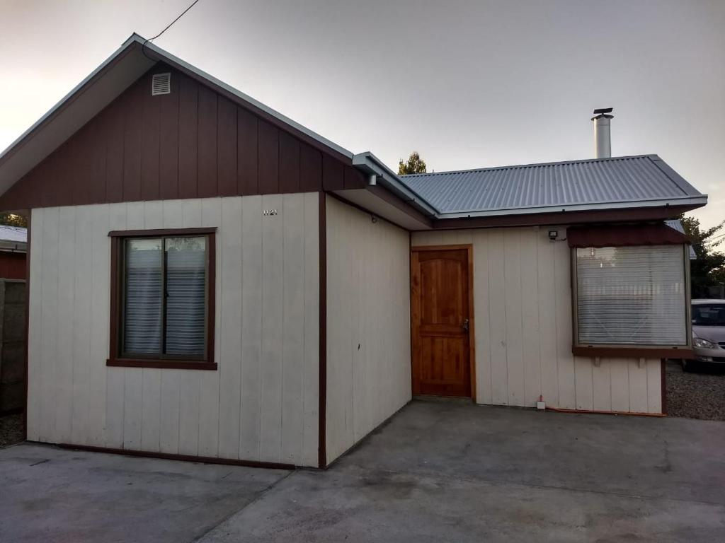 a white and brown house with a garage at Cabaña Centro Pitrufquen in Pitrufquén