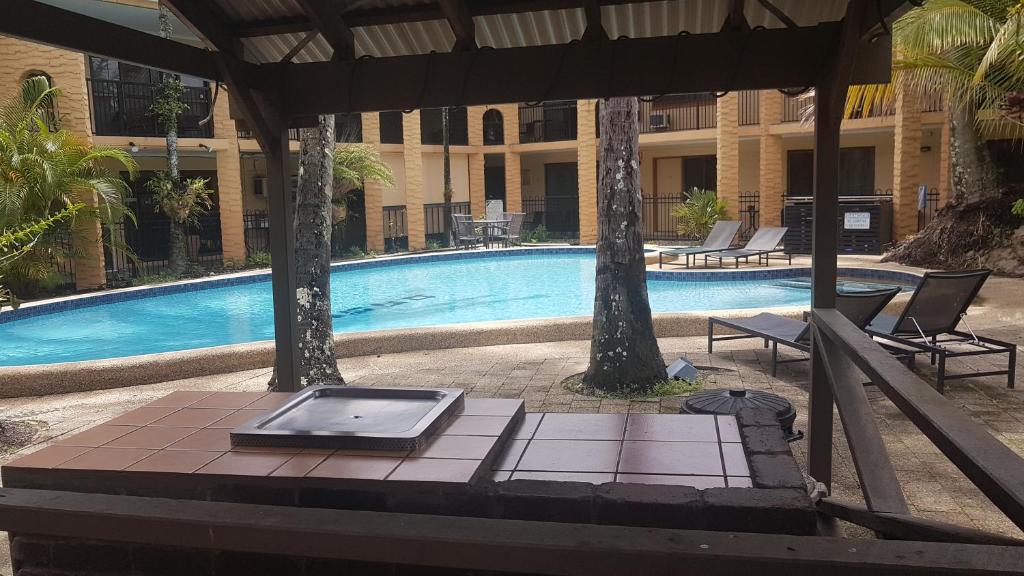 a swimming pool with a laptop on a table in front of a building at Oasis Inn Apartments in Cairns