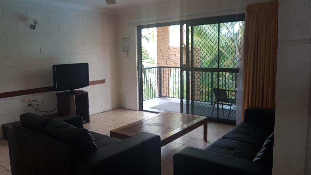 a living room with two couches and a table and a television at Oasis Inn Apartments in Cairns