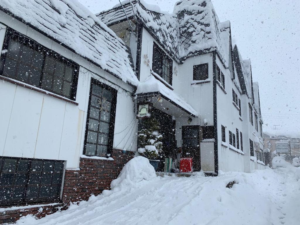 a house covered in snow with a pile of snow at Bamboo-Hill Sasaoka in Nozawa Onsen