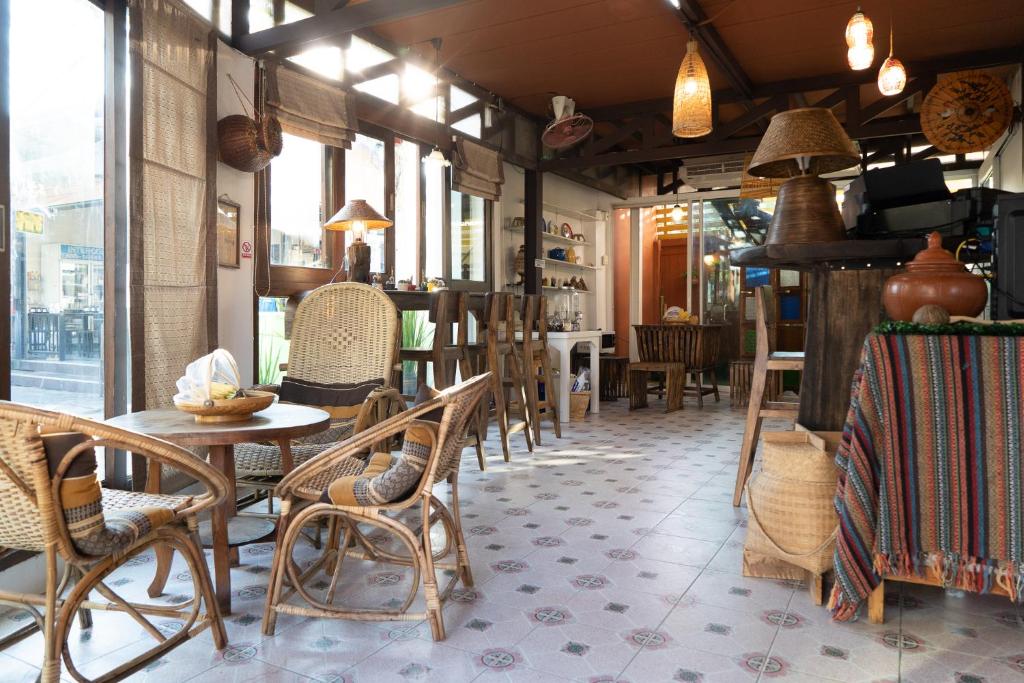 a restaurant with chairs and tables and windows at Past Tense Hostel in Chiang Mai