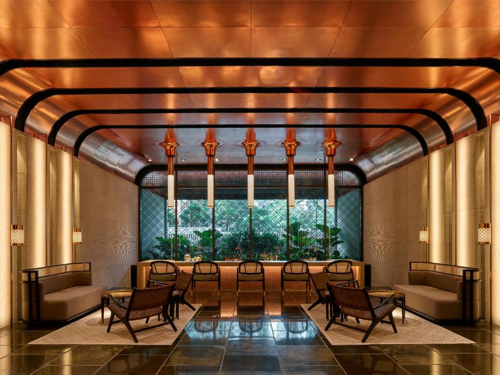 a lobby with chairs and a table and a large window at The RuMa Hotel and Residences in Kuala Lumpur