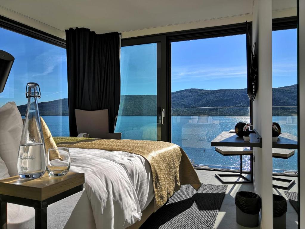 Sky Beach Aparthotel في مارينا: غرفة نوم بسرير ونافذة زجاجية كبيرة