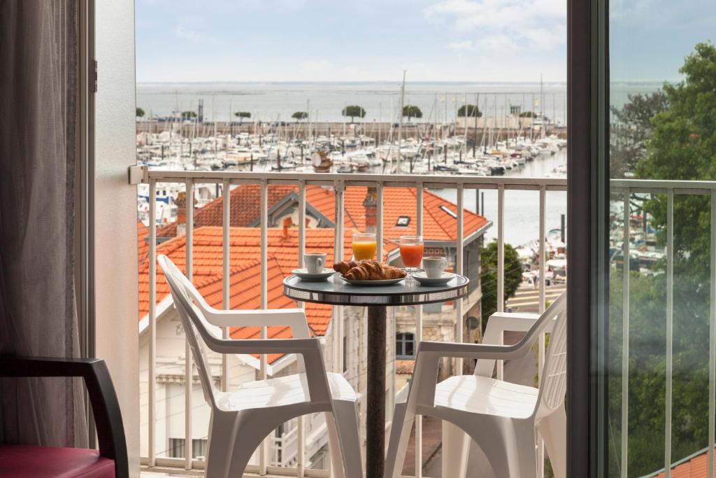 a table on a balcony with a view of a marina at Hôtel Le Nautic in Arcachon