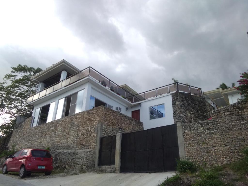 una casa dietro un muro di mattoni con una macchina rossa parcheggiata di fronte di Seaview Mansion Dalaguete Apartment 4 -Family a Dalaguete