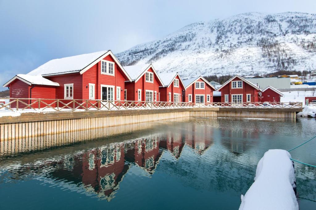 una fila de casas rojas frente a una montaña cubierta de nieve en XLyngen, en Nord-Lenangen