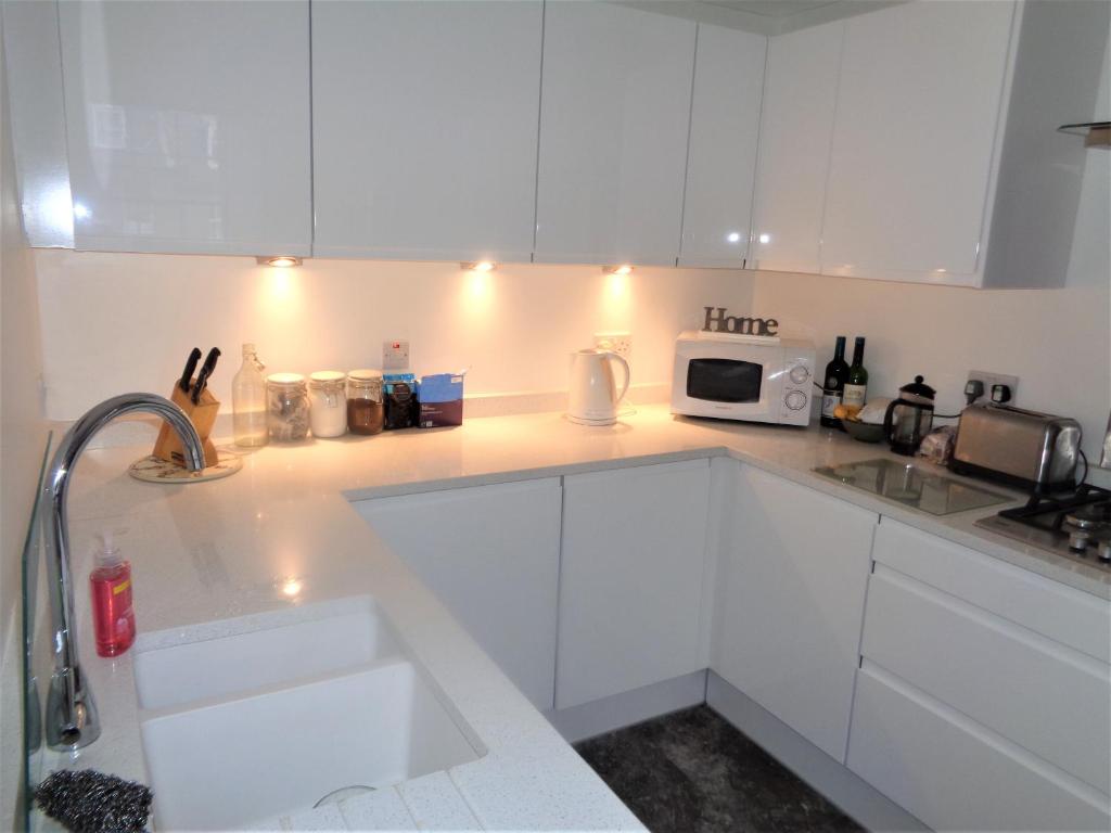 Una cocina blanca con fregadero y microondas. en Heritage City - Central York Place Apt, en Edimburgo