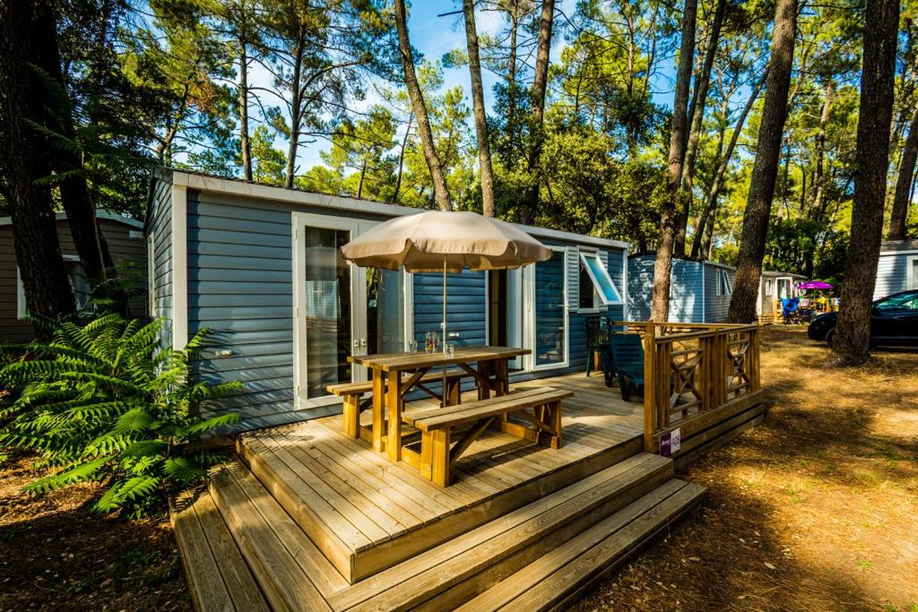 una terraza de madera con mesa y sombrilla en Camping la Sousta****, en Remoulins