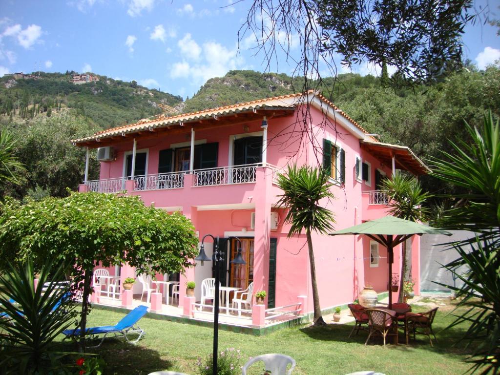 una casa rosa con una mesa y sillas en un patio en Ipsia Apartments, en Paleokastritsa