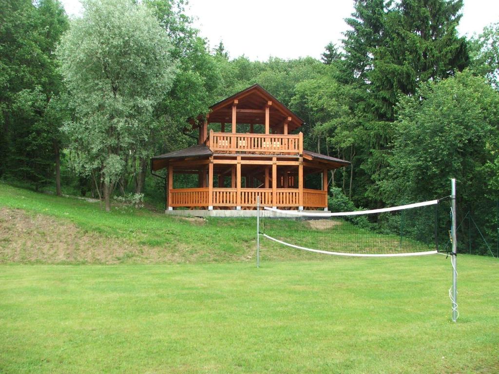 a large wooden house with a volleyball net in a field at Holiday Park Orava - Hotel Orava in Dolný Kubín
