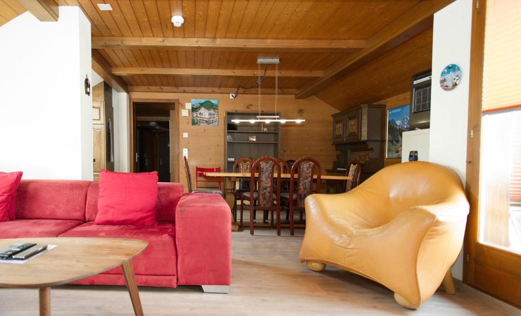 インターラーケンにあるRössli Holiday Apartmentのリビングルーム(赤いソファ、テーブル付)