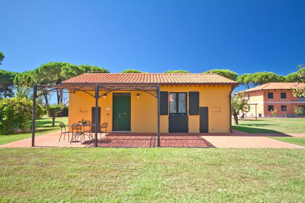 a small yellow house with a table in a yard at La Fattoria di Tirrenia in Tirrenia