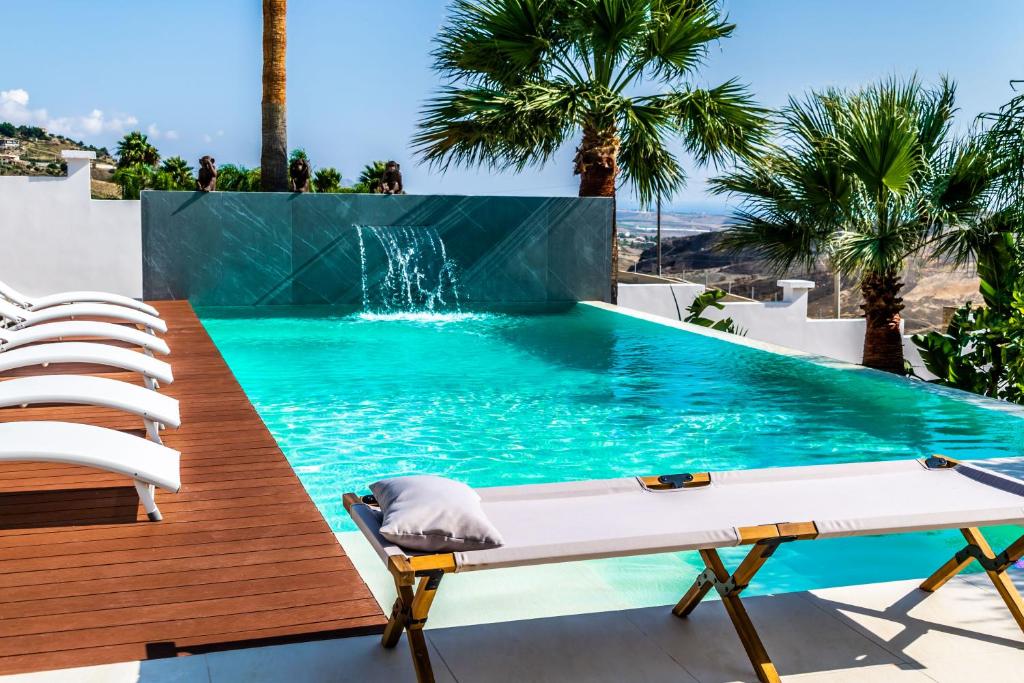 a pool with a table and chairs and a waterfall at Diodorus Luxury Experience in Favara