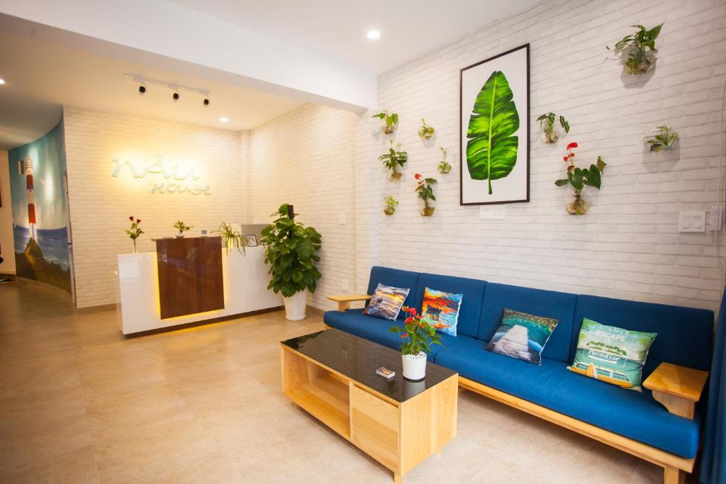 a living room with a blue couch and plants on the wall at Nẫu House in Tuy Hoa