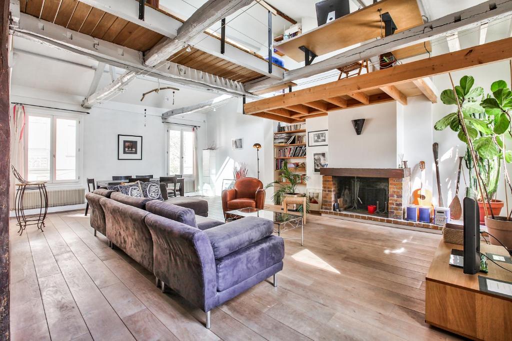 un salon avec un canapé et une cheminée dans l'établissement Charming duplex Bastille by weekome, à Paris