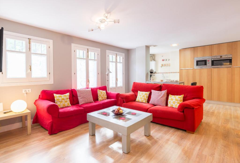 a living room with two red couches and a table at Mundo Nuevo: Acogedor Apartamento en el Centro in Málaga