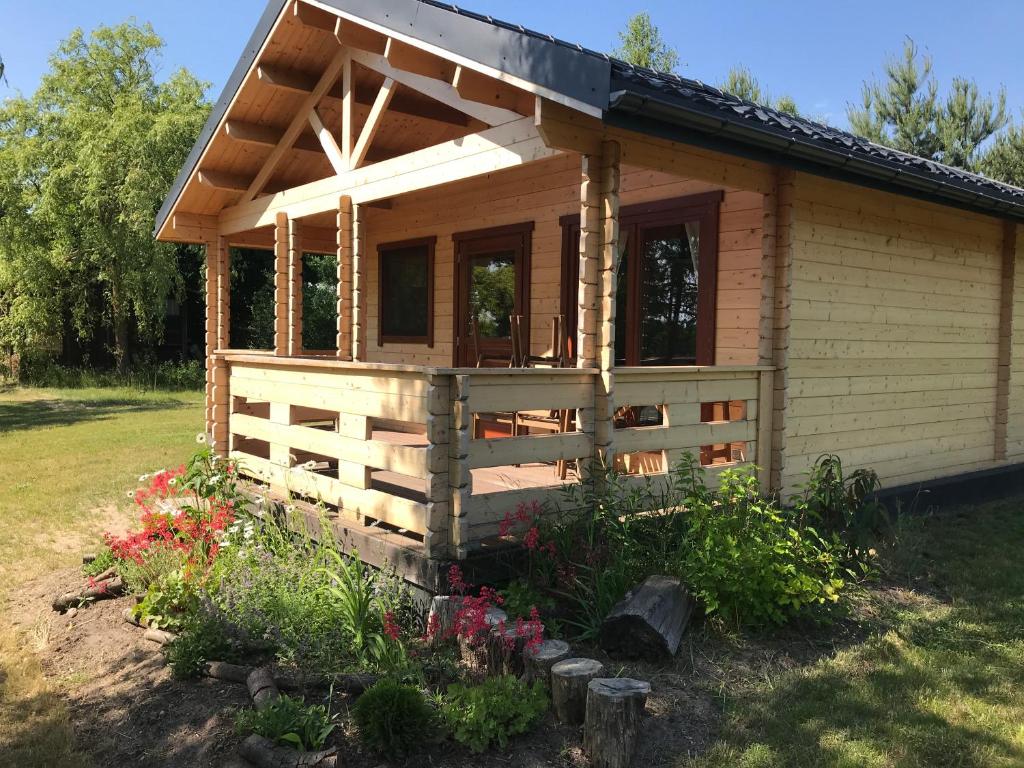 una piccola cabina in legno con recinzione e fiori di Borowiak a Szteklin