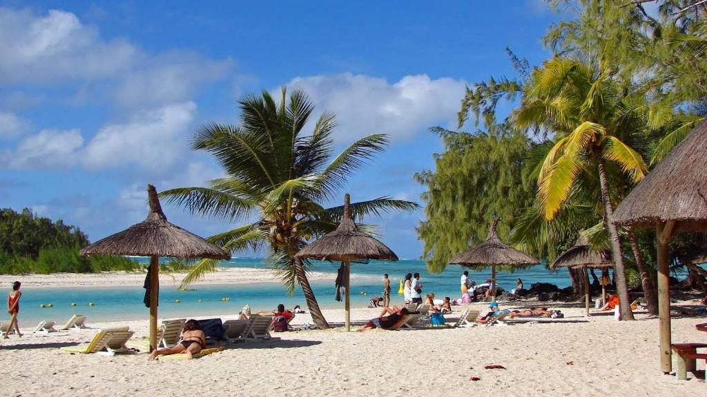 a group of people on a beach with umbrellas at Golden Rod villa in Belle Mare