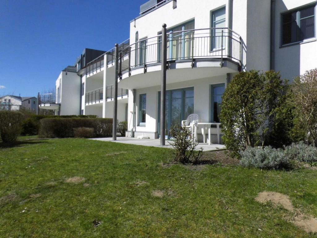 - un bâtiment blanc avec un balcon et une pelouse dans l'établissement 54 Appartement Residenz Bellevue U, à Zinnowitz