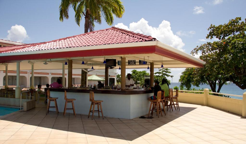 a restaurant with a bar with people sitting at it at Crown Point Beach Hotel in Crown Point