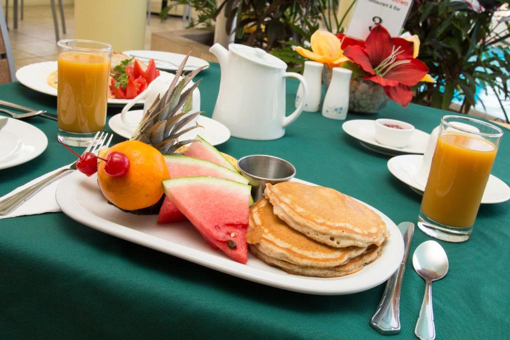 a plate of pancakes and fruit on a table at Crown Point Beach Hotel in Crown Point