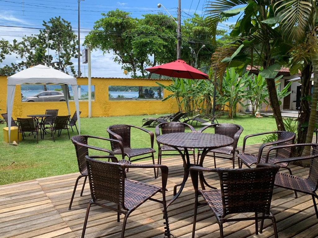 a patio with tables and chairs and a red umbrella at Beira Mar in Ubatuba