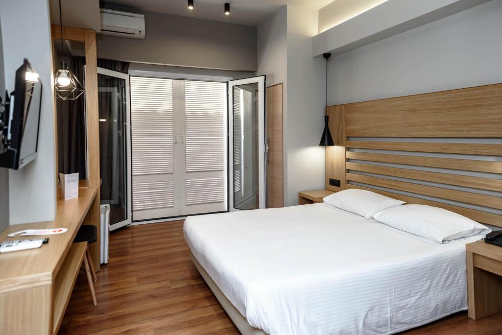 a bedroom with a large white bed and a desk at Agamemnon Hotel in Nafplio