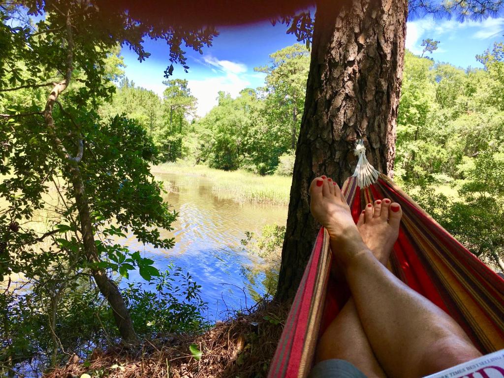 a person laying in a hammock next to a tree at The Dock House in Calabash