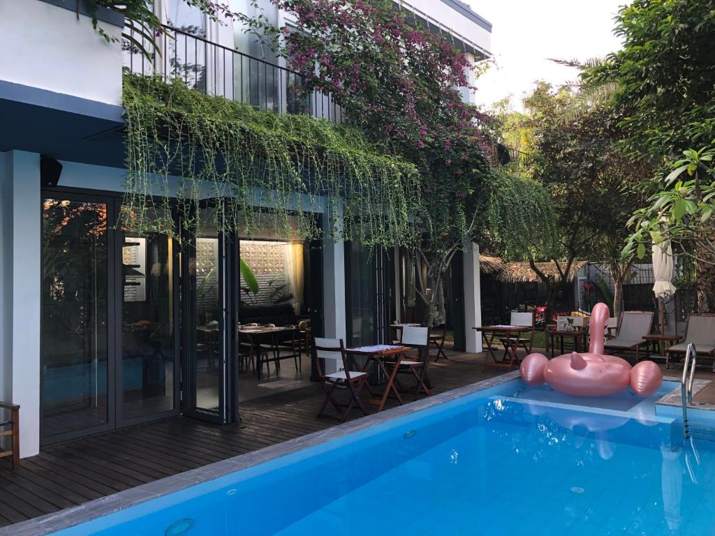 a swimming pool with a house with a pink swan next to it at An Bang beach Chay Villas in Hoi An