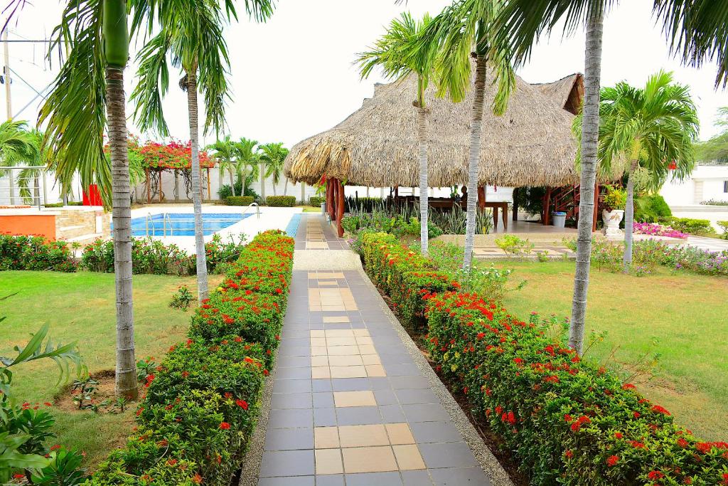 a walkway leading to a resort with flowers and palm trees at Hotel Emerawaa in Ríohacha